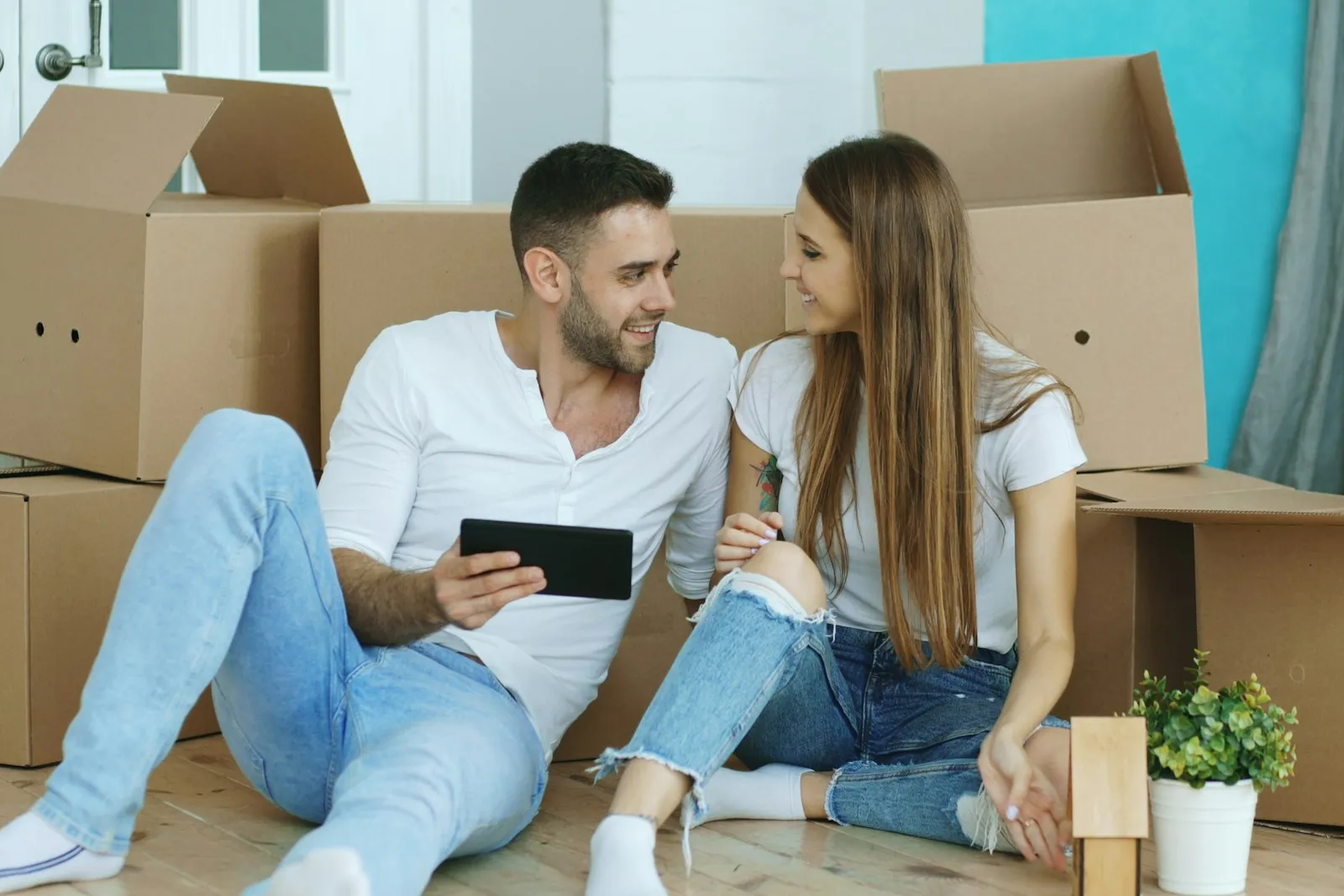 Couple consultant une tablette entouré de cartons de déménagement