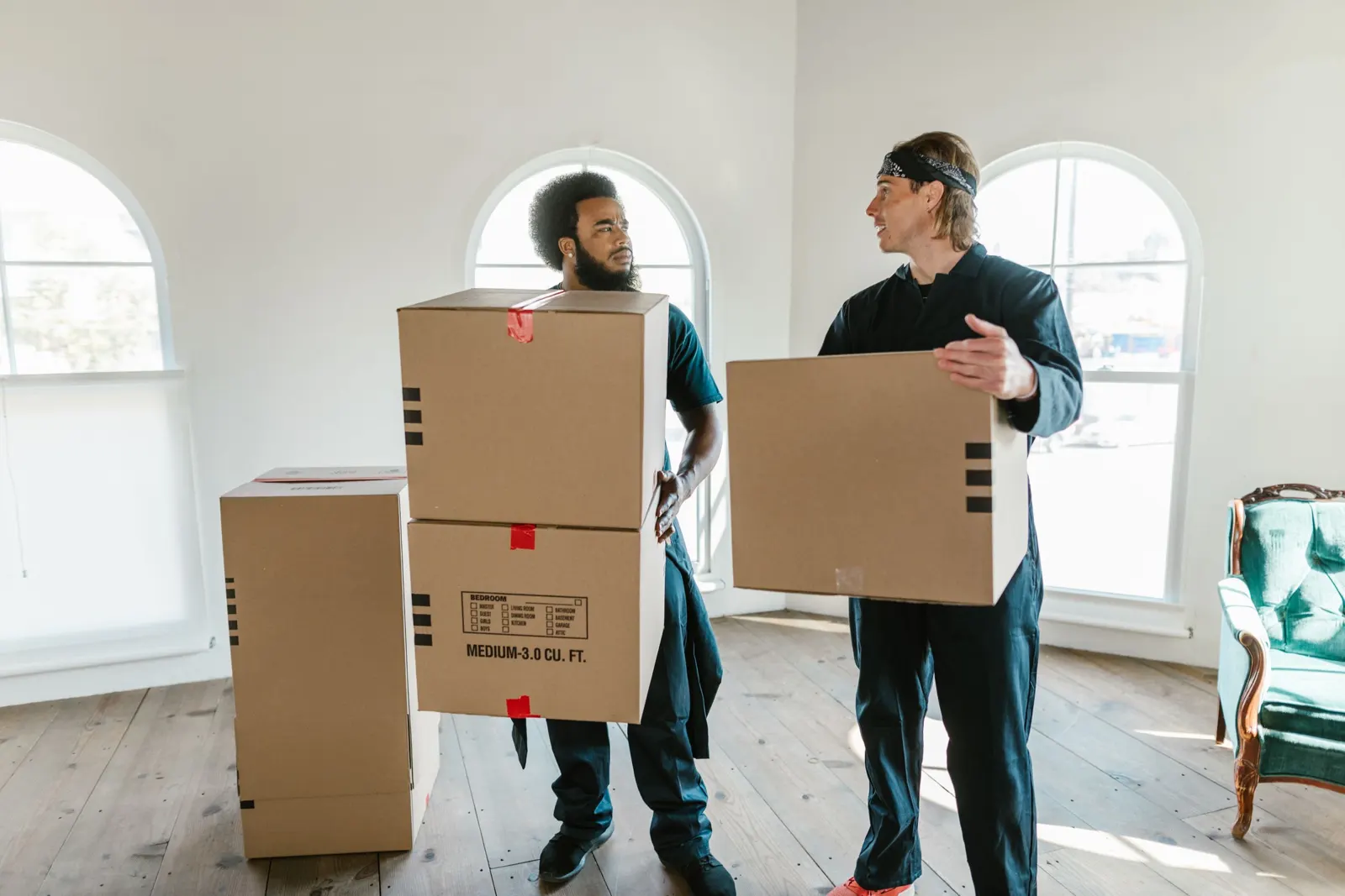 Deux déménageurs transportant des cartons dans un logement lumineux