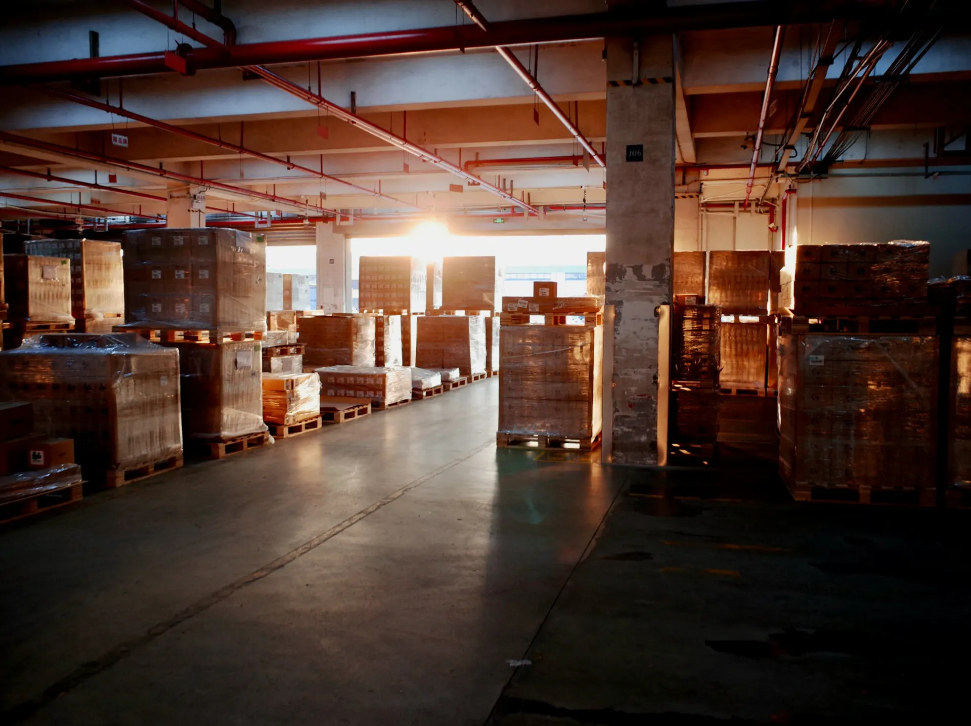Entrepôt logistique avec marchandises sur palettes, éclairé en soirée